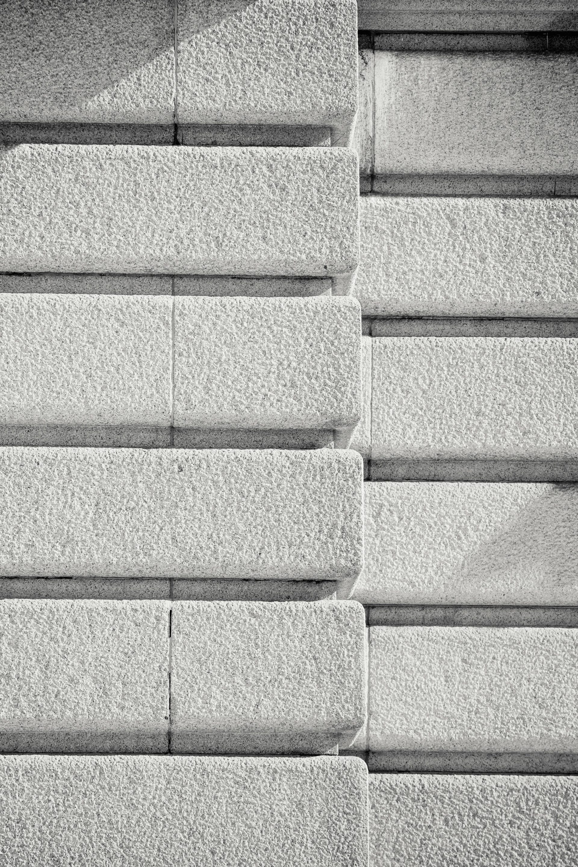 Close-up of a symmetrical textured concrete wall in black and white, emphasizing pattern and detail.