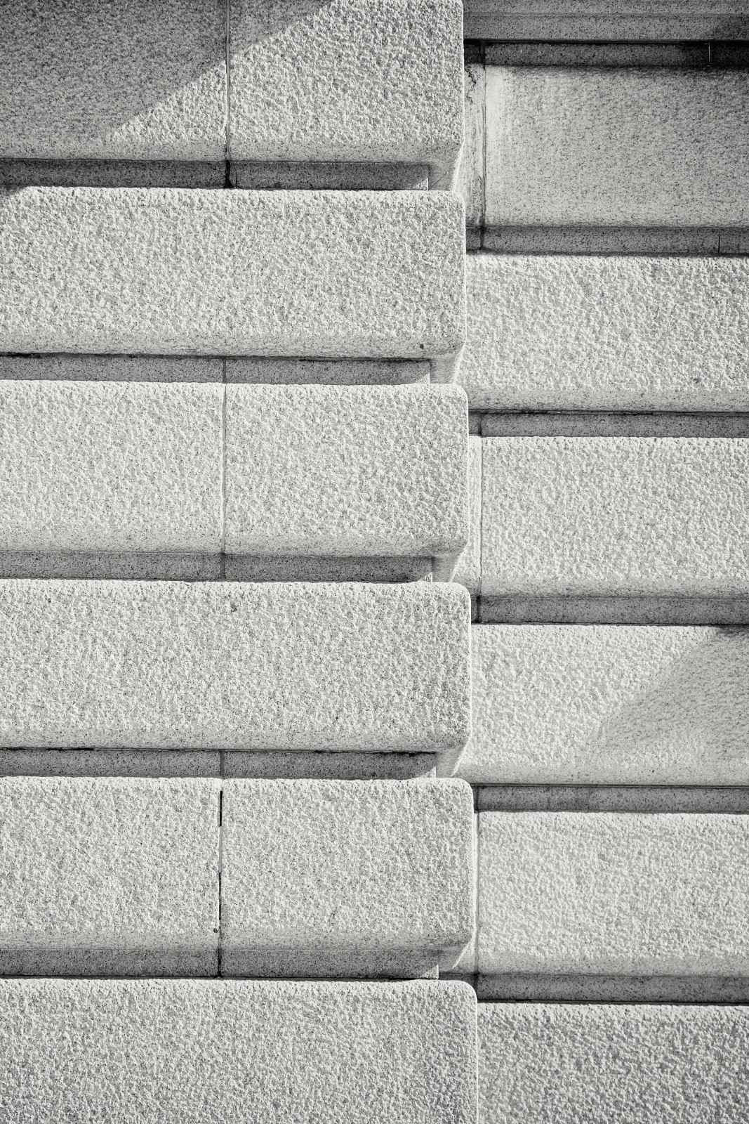 Close-up of a symmetrical textured concrete wall in black and white, emphasizing pattern and detail.