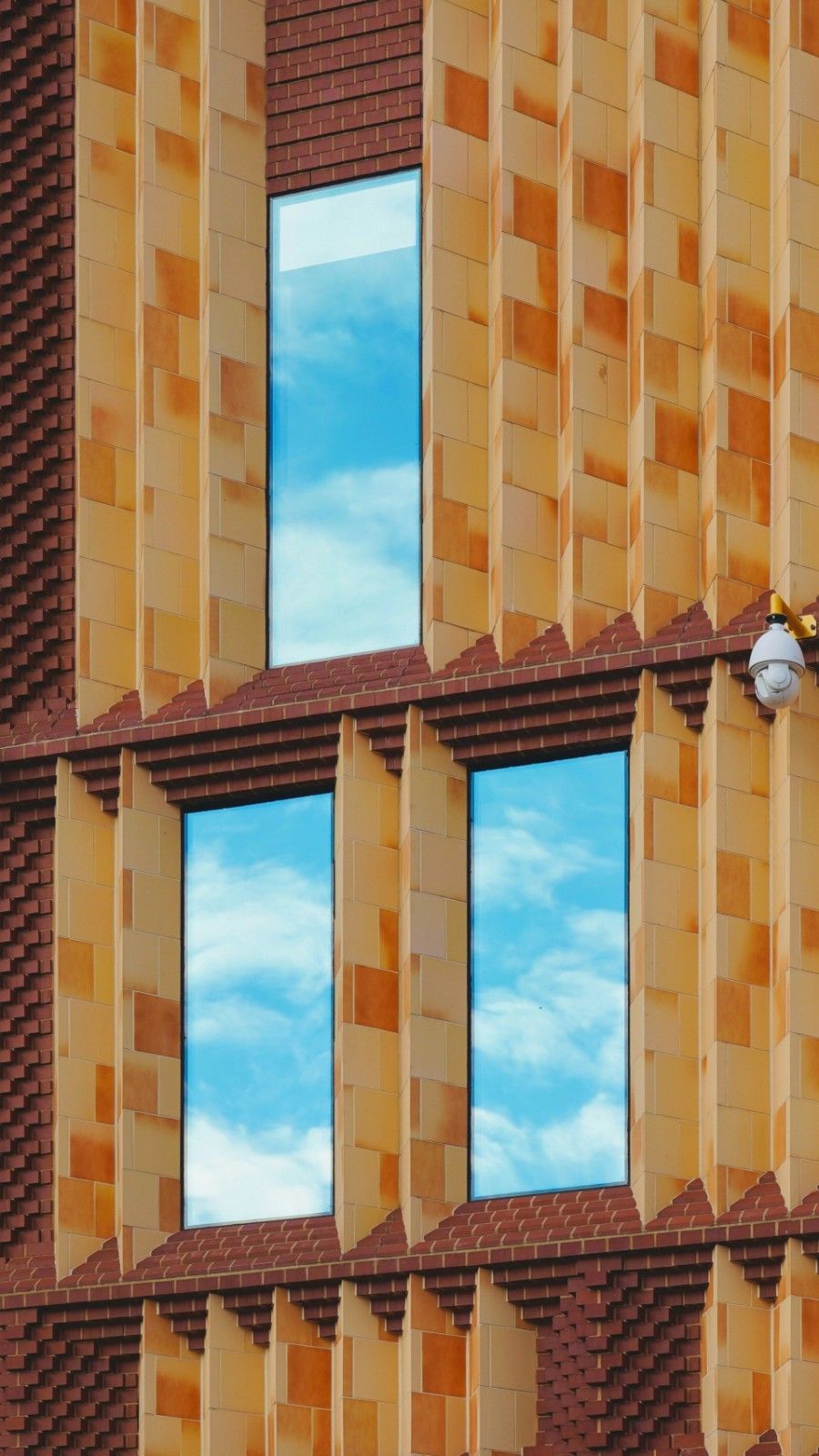 Modern building facade with reflective windows showing clouds